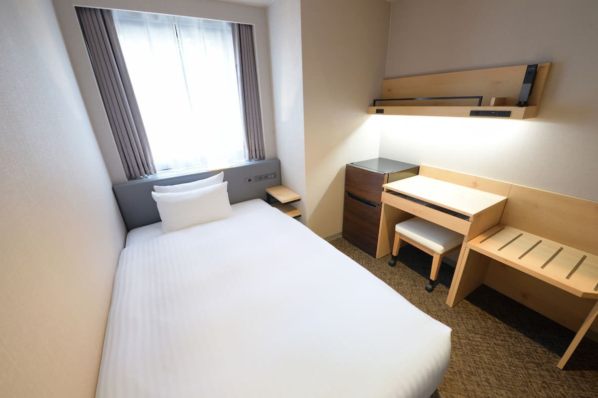 Une chambre d’hôtel avec un lit, un bureau et une chaise.