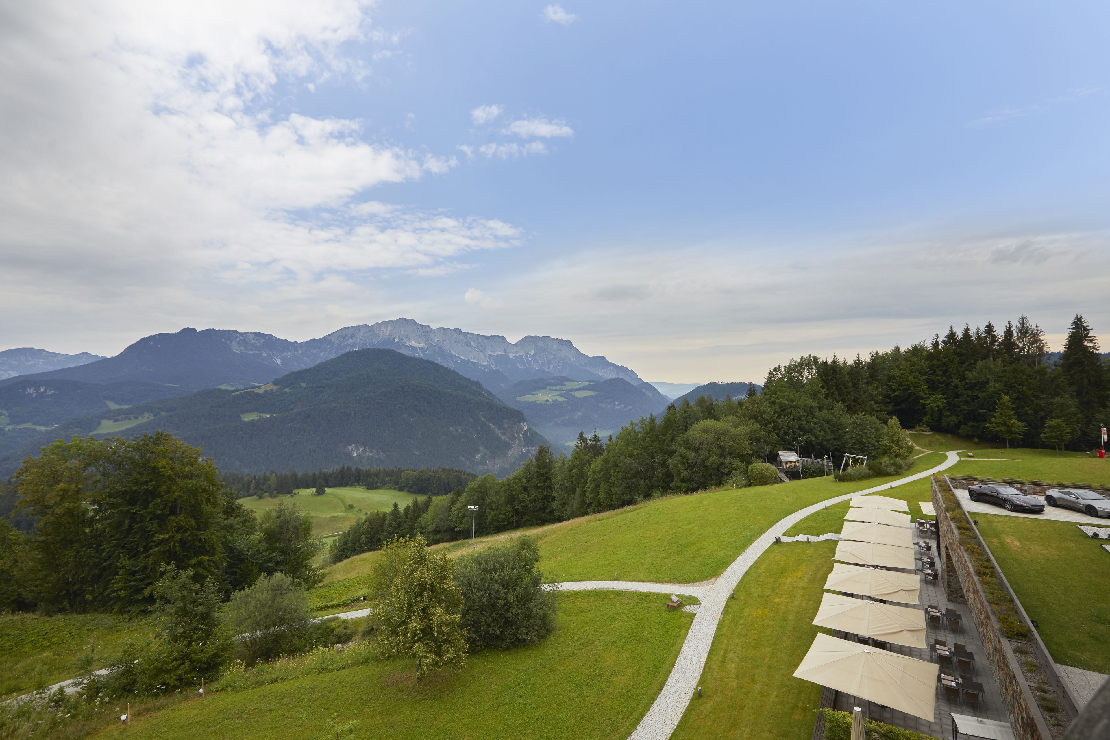 A scenic view of a mountainous landscape with a pathway leading to a covered outdoor seating area.