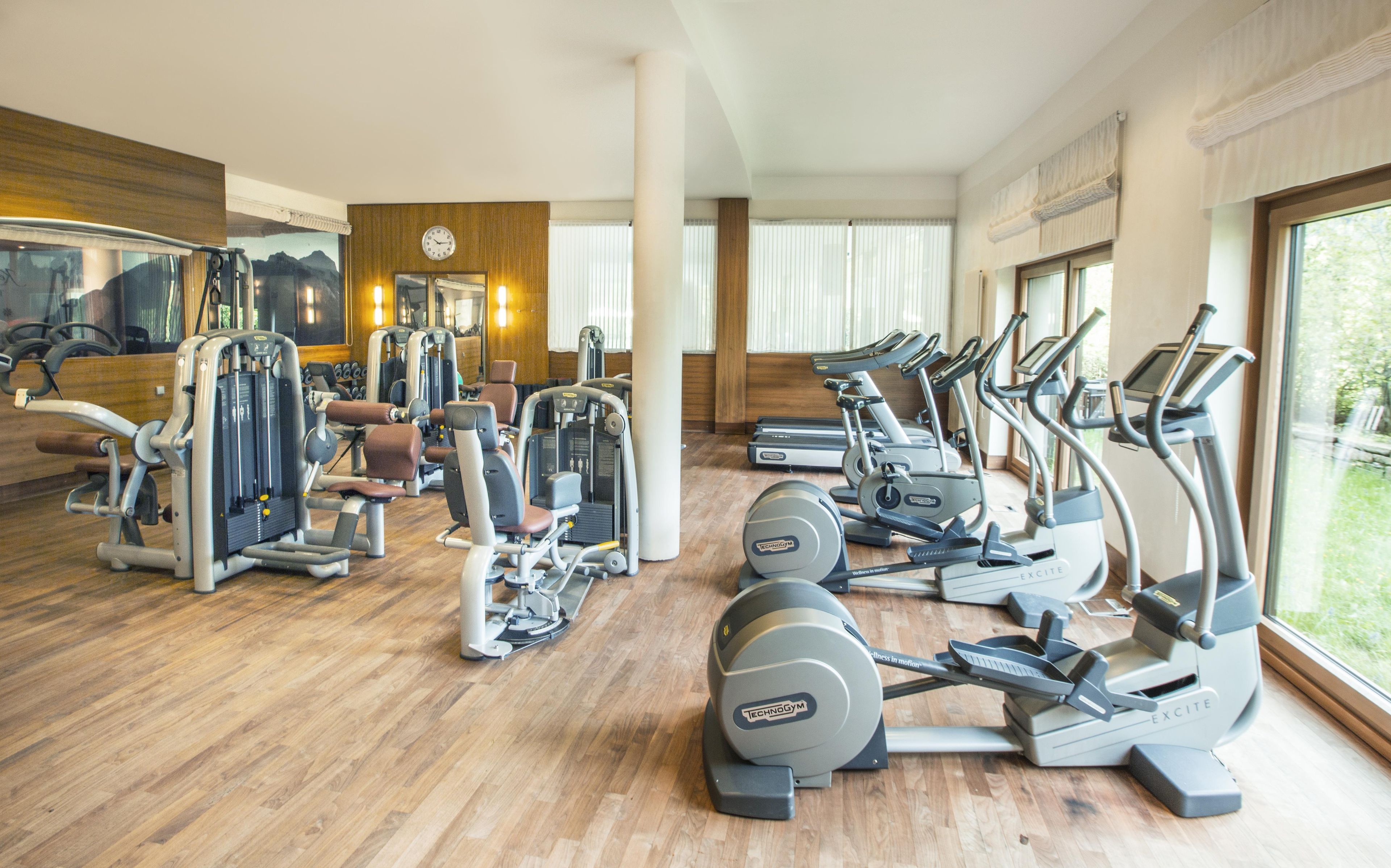 Ein Fitnessstudio mit verschiedenen Trainingsgeräten, darunter Laufbändern und Kraftmaschinen, und großen Fenstern, die für natürliches Licht sorgen.