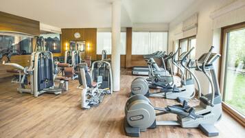 Ein Fitnessstudio mit verschiedenen Trainingsgeräten, darunter Laufbändern und Kraftmaschinen, und großen Fenstern, die für natürliches Licht sorgen.