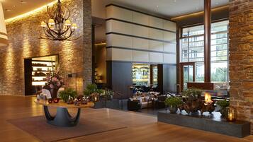 A modern lobby with a stone wall, a chandelier, and a seating area with a fireplace.