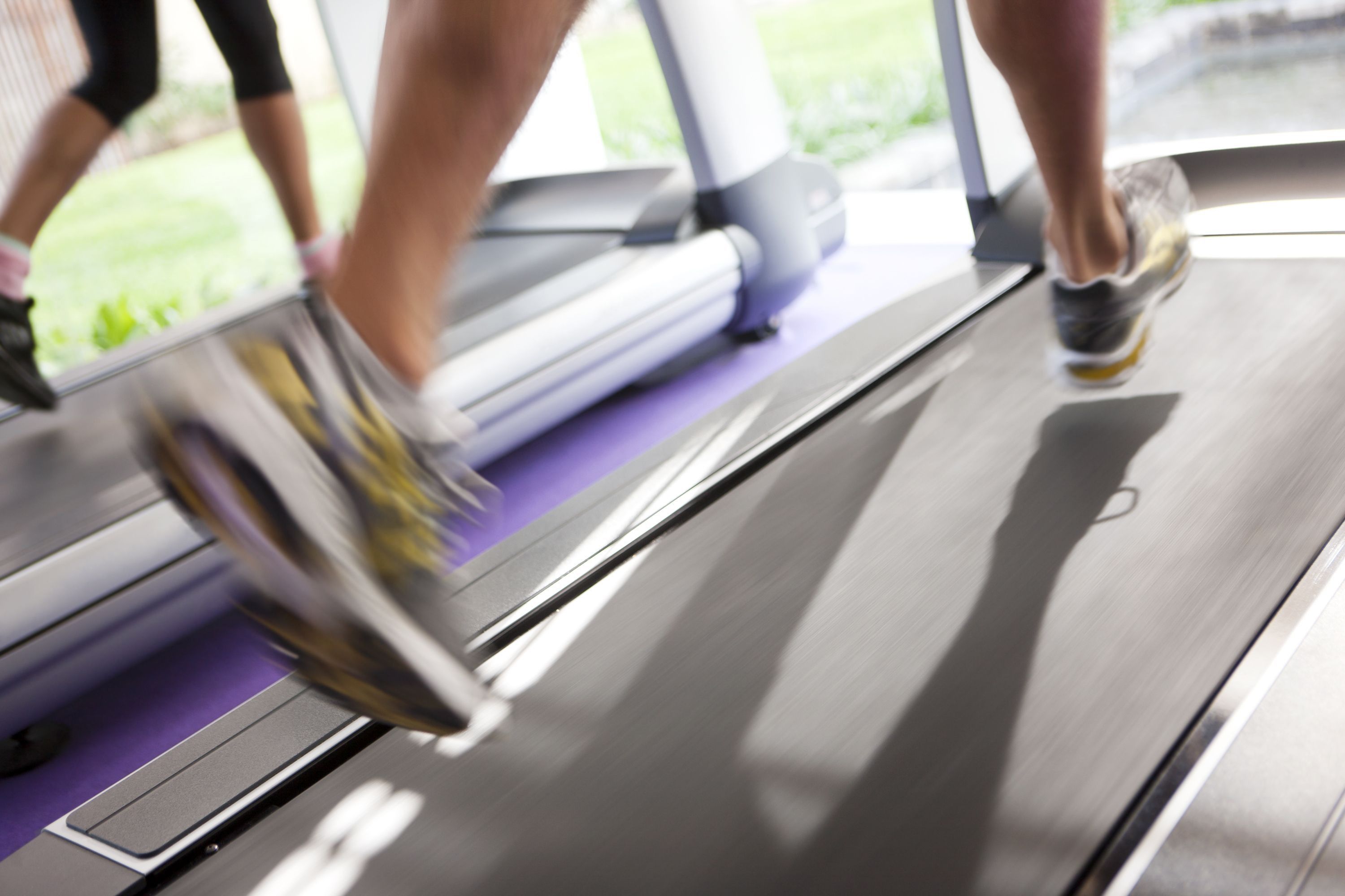 A close-up of a treadmill with a metallic frame and a purple floor mat.