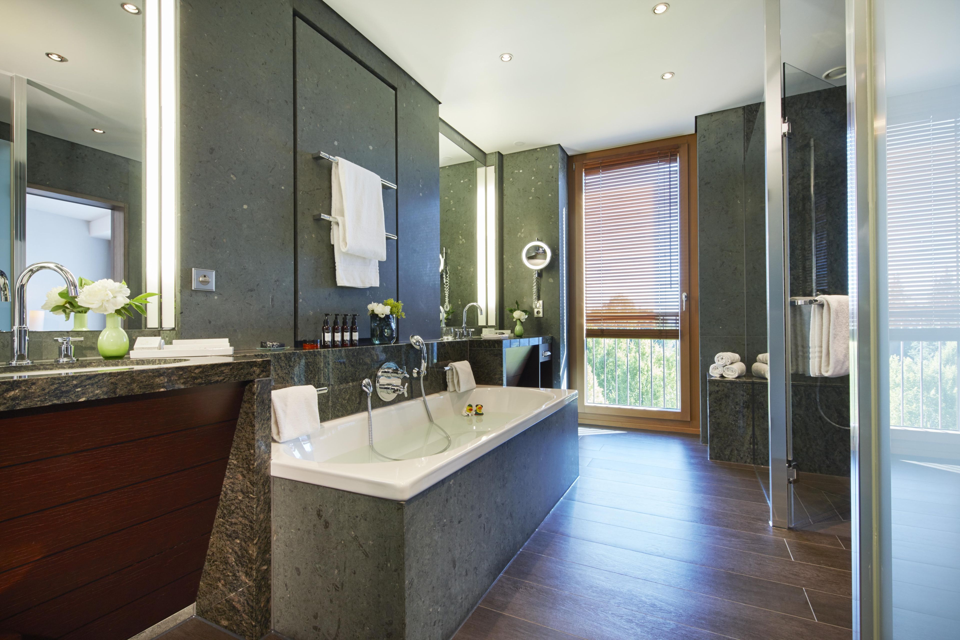 A modern bathroom with a large bathtub, a vanity with a mirror, and a shower area.