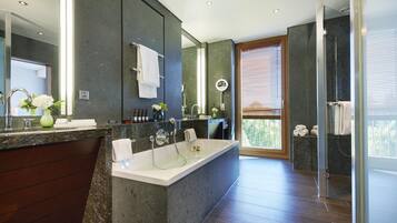 A modern bathroom with a large bathtub, a vanity with a mirror, and a shower area.