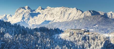 A hotel nestled in a snowy mountainous area with a clear view of the surrounding peaks.
