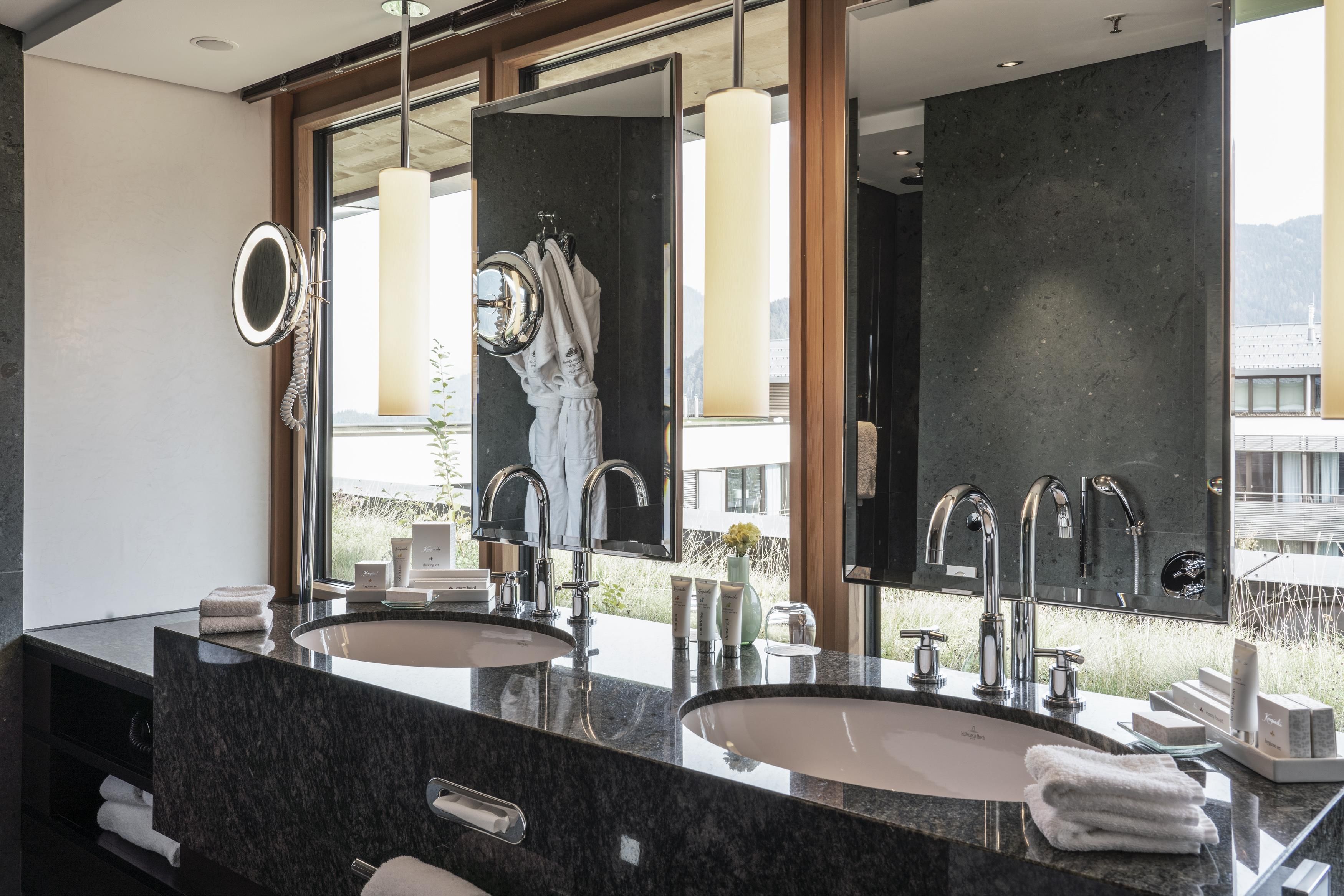 Ein modernes Badezimmer mit zwei Waschbecken, einem großen Spiegel und Blick auf ein Gebäude.