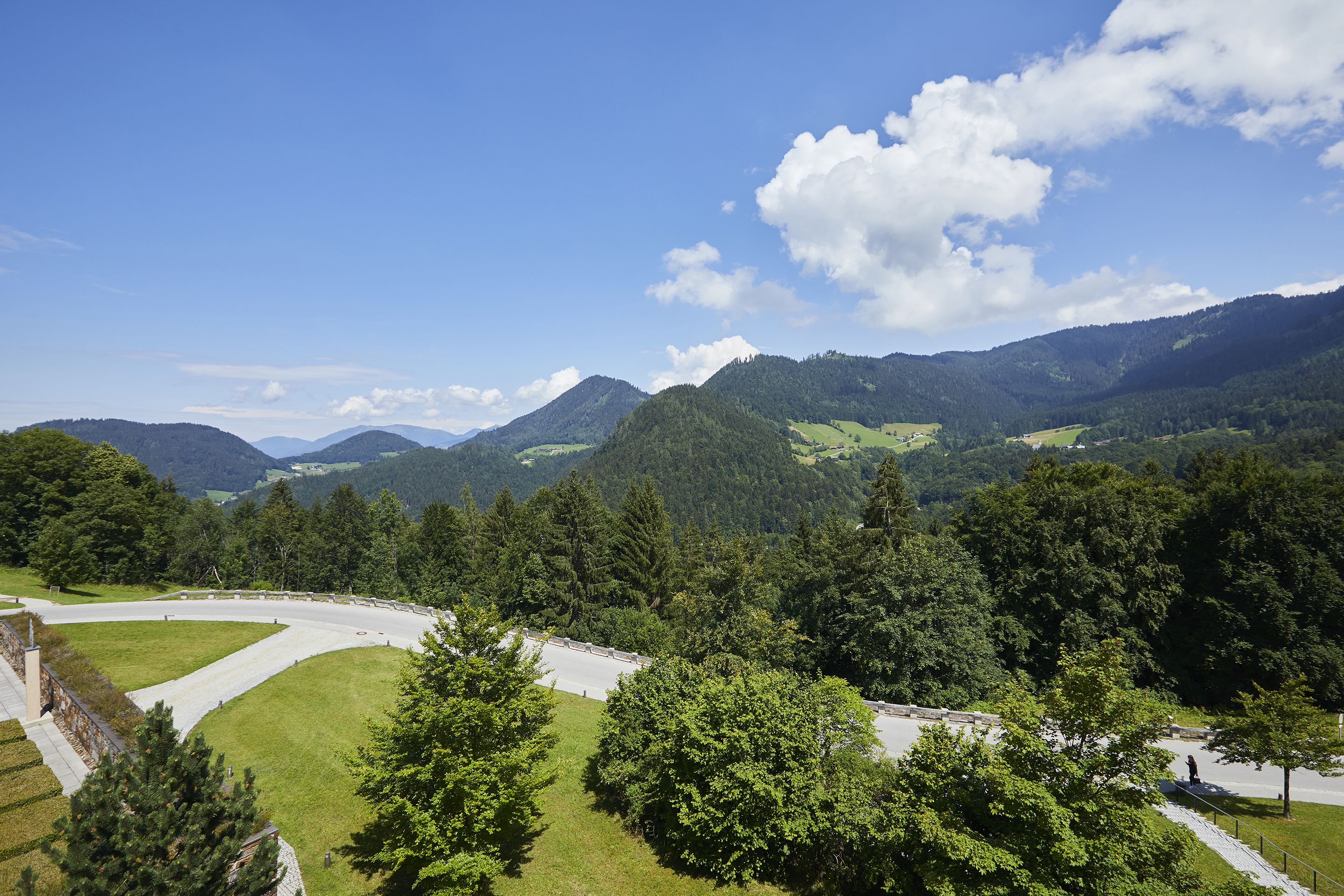 Eine gebirgige Landschaft mit einer kurvenreichen Straße und dichtem Wald.