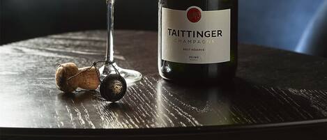 Eine Flasche Taittinger Champagner und ein Glas mit Bläschen auf einer Holztisch.