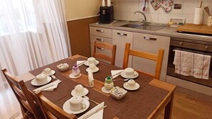 A dining area with a table set for tea, a coffee machine, and a kitchen with a stove and sink. - Domina Popolo B&B (Rome)