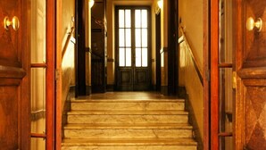 A grand staircase with marble steps leading to a door with a large window. - Domina Popolo B&B (Rome)