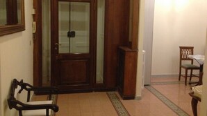 A wooden door with glass panels, a bench, a chair, and a radiator. - Domina Popolo B&B (Rome)