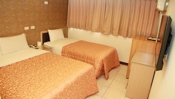A hotel room with two beds, a desk, a television, and a window with curtains.