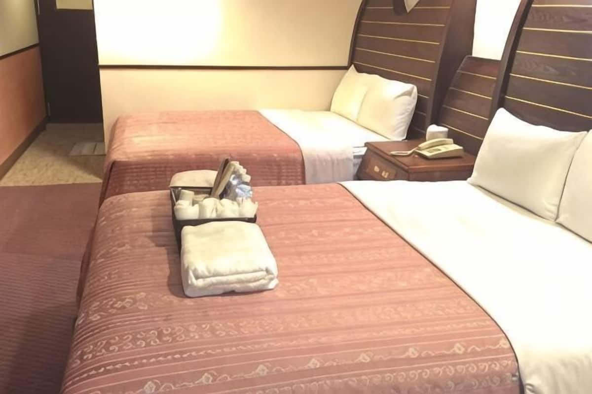 A hotel room with two beds, a nightstand, and a telephone.