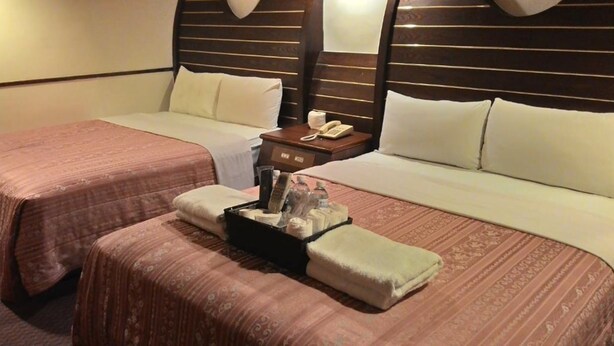 Habitación de hotel con dos camas, una mesita de noche con teléfono y una bandeja con artículos de aseo.