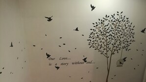 A wall with a tree and birds, and a quote saying "Our Love... is a story without end...".