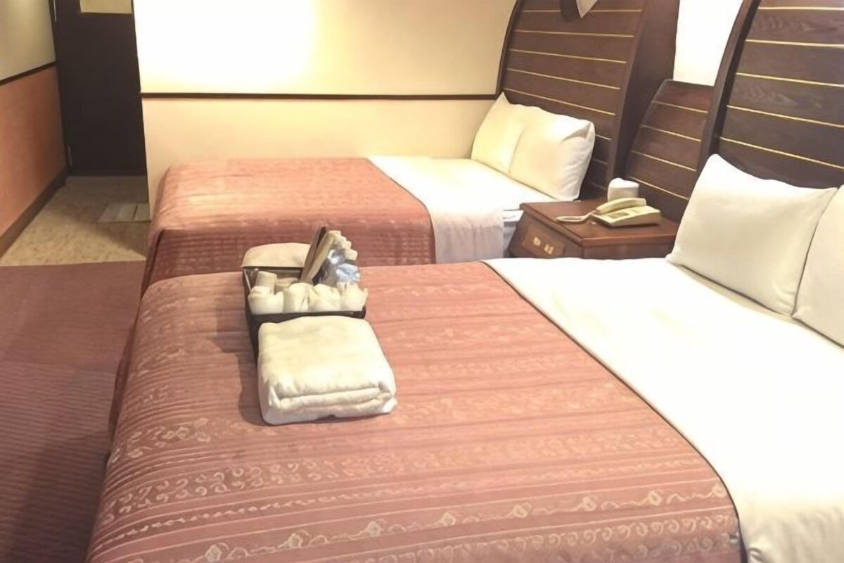 Habitación de hotel con dos camas, una mesita de noche y un teléfono.
