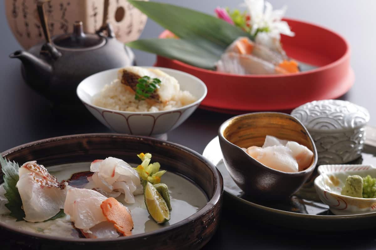 Ein traditioneller japanischer Essensaufbau mit verschiedenen Gerichten, darunter Reis, Sashimi und einem Teekessel.