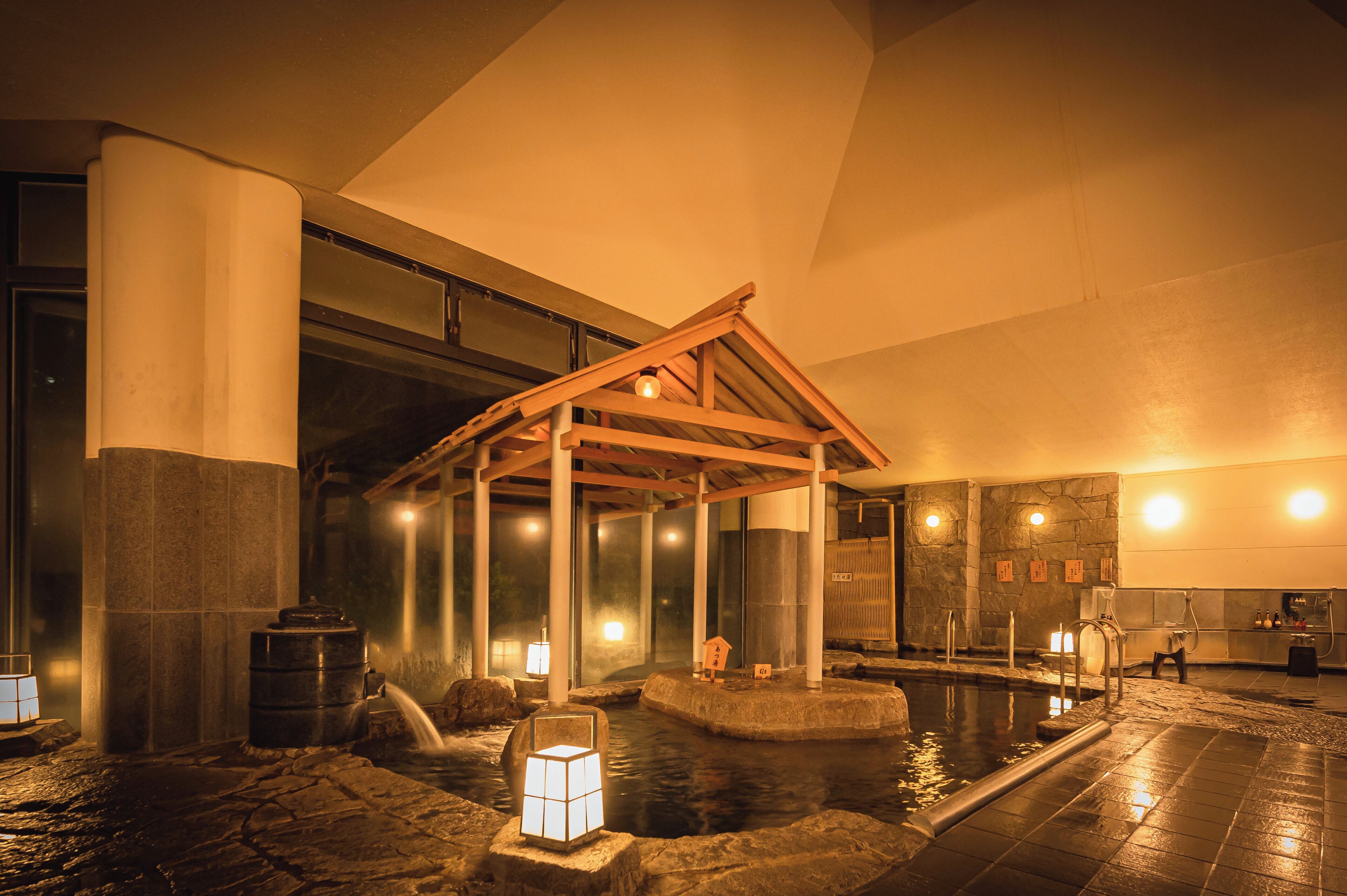 A traditional Japanese onsen with stone baths, wooden structures, and ambient lighting.