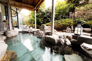 A traditional Japanese garden with a stone pond, rocks, and a wooden pavilion. - Dogo-Kan (Matsuyama)