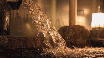 A close-up of water flowing from a faucet into a basin.