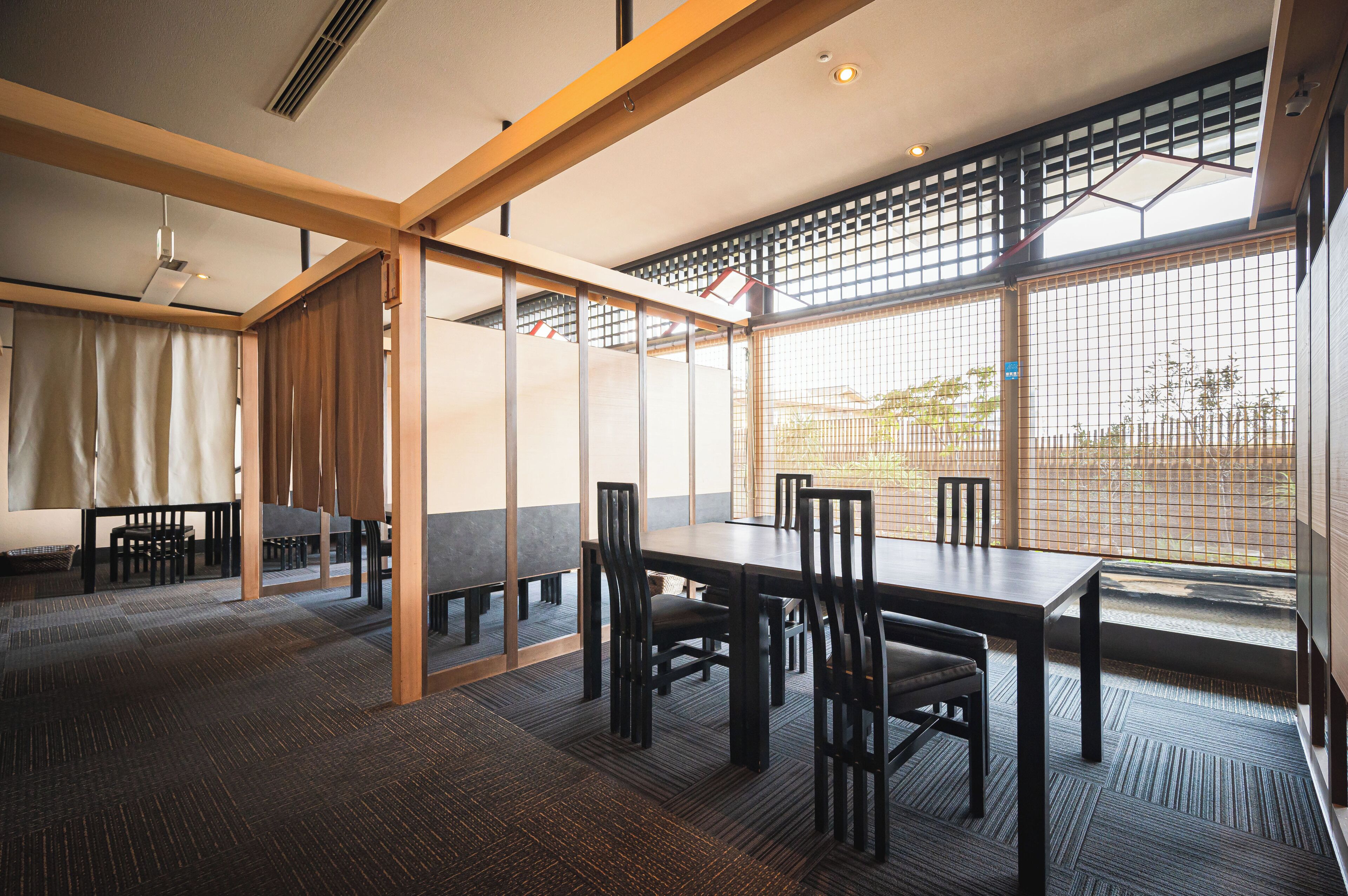 A modern dining area with a long table and chairs, large windows with a view, and a traditional sliding door.