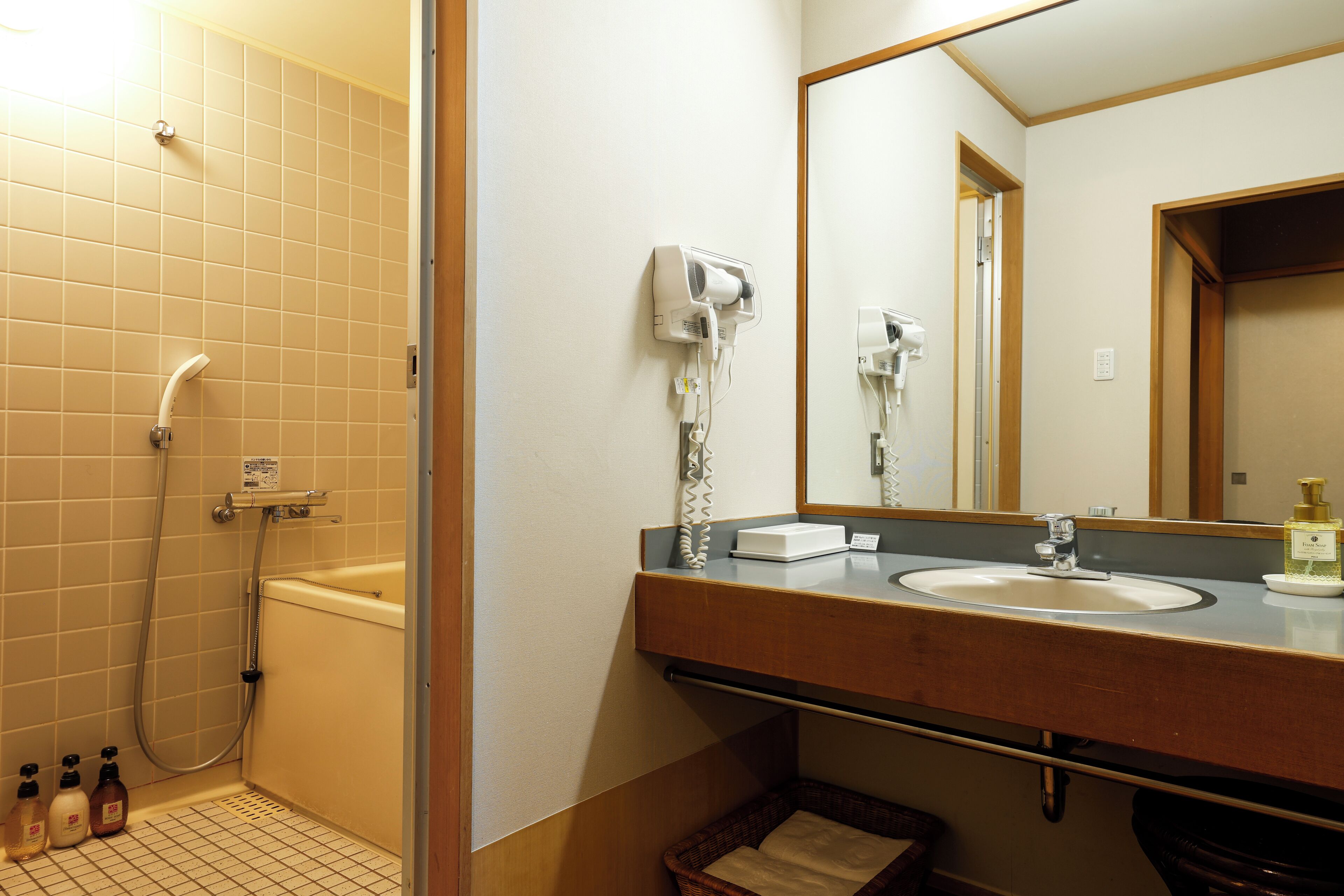Une salle de bain équipée d’une baignoire, d’un lavabo, d’un miroir et d’un sèche-cheveux fixé au mur.