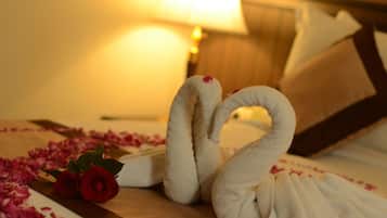 Un lit avec une tête de lit en bois, un oreiller blanc et une serviette décorative en forme de cygne.