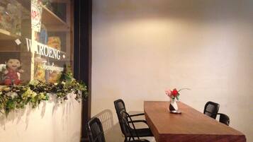 Un comedor con una mesa de madera y cuatro sillas, un jarrón con flores y una ventana con un letrero.