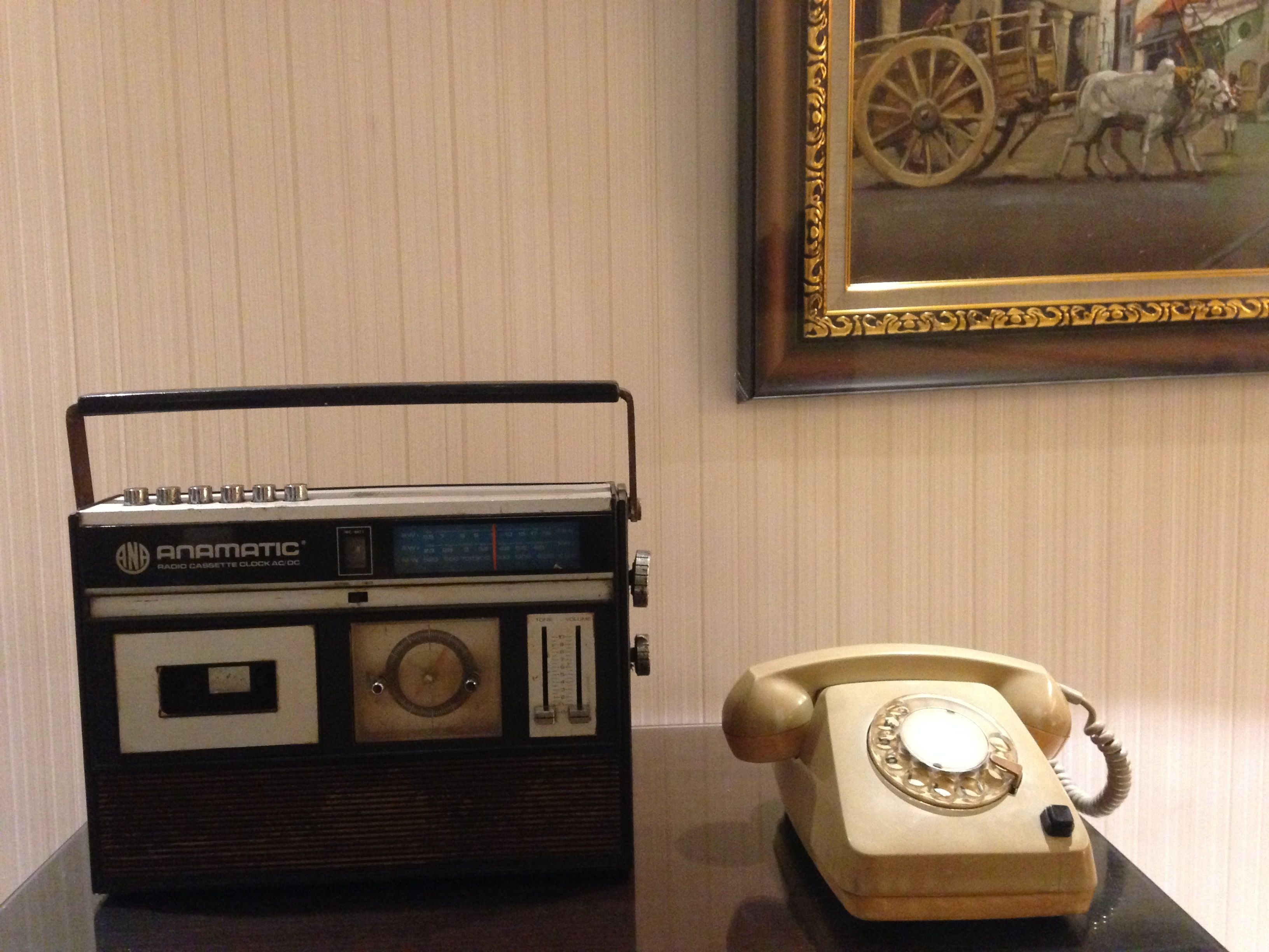 A vintage radio and a rotary dial telephone on a table.