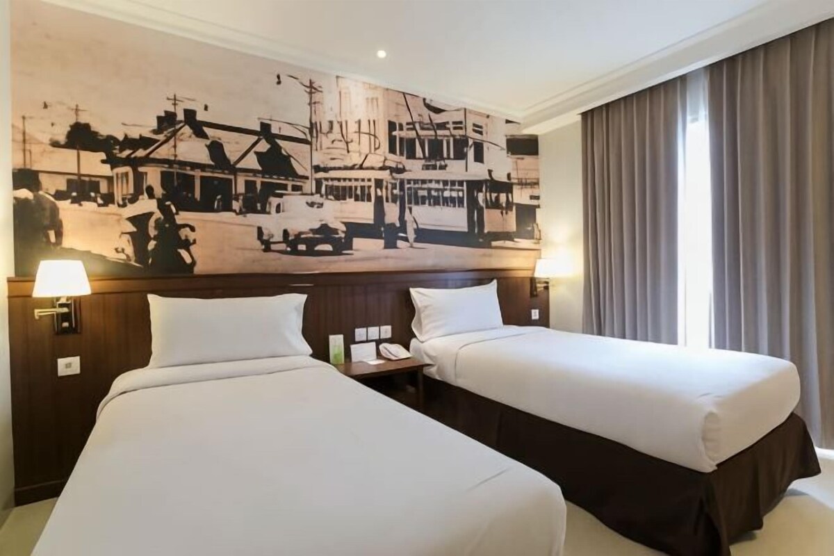 Habitación de hotel con dos camas, un mural grande en la pared y una ventana con cortinas.