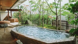 A hot spring area with a stone pool, wooden deck, and surrounding greenery. - Kinugawa Kanaya Hotel (Nikko)