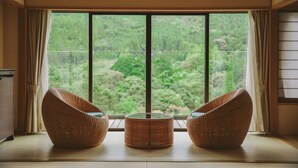 A room with a large window, two wicker chairs, and a small round table. - Kinugawa Kanaya Hotel (Nikko)