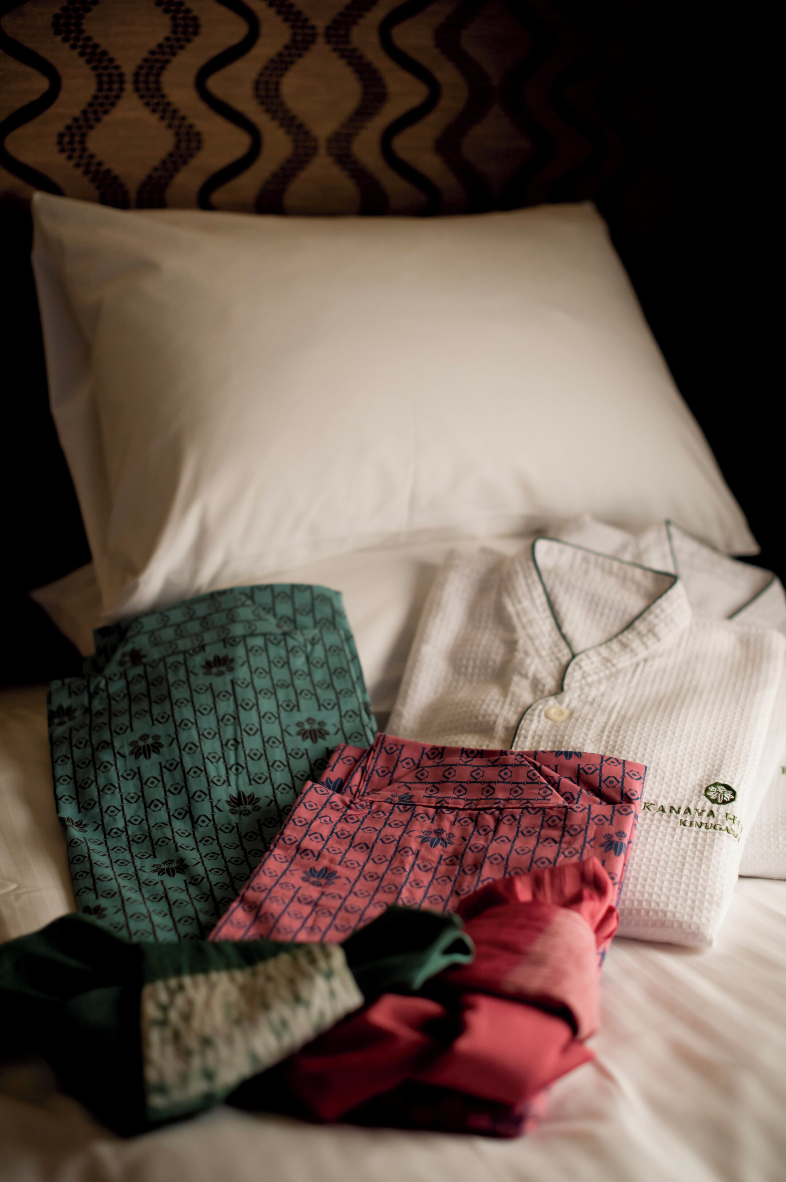 A bed with pillows and folded shirts.