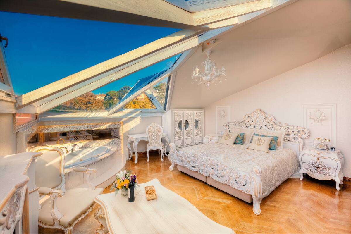 Un dormitorio con tragaluz, cama ornamentada y un escritorio con silla.