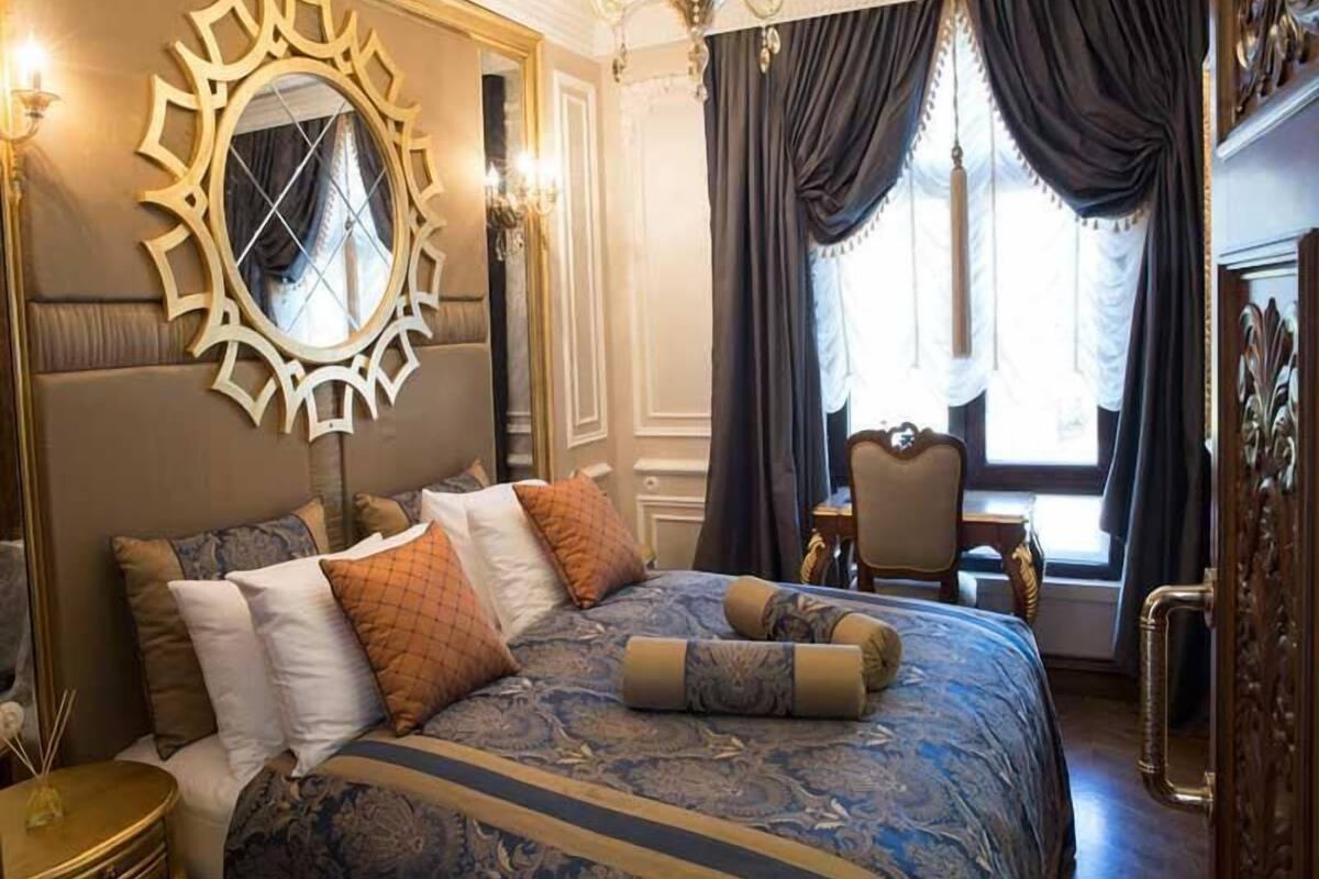 Un dormitorio lujoso con una cama grande, un espejo ornamentado y una decoración elegante.
