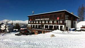 Hotel Club Monte Triplex con un letrero llamativo, rodeado de montañas nevadas.