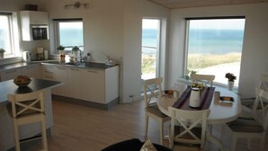 Una cucina moderna con mobili bianchi, forno integrato e un'ampia finestra vista spiaggia.
