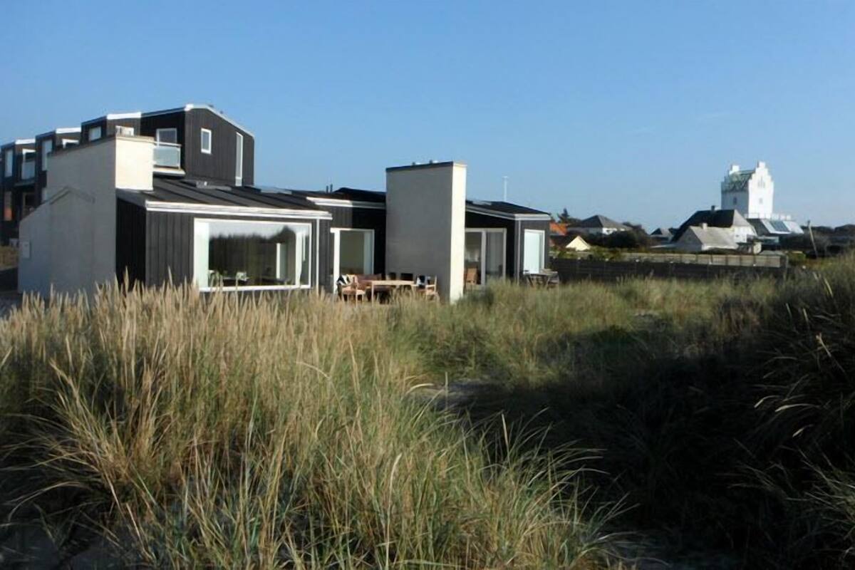 A modern building with large windows and a flat roof, surrounded by tall grass.