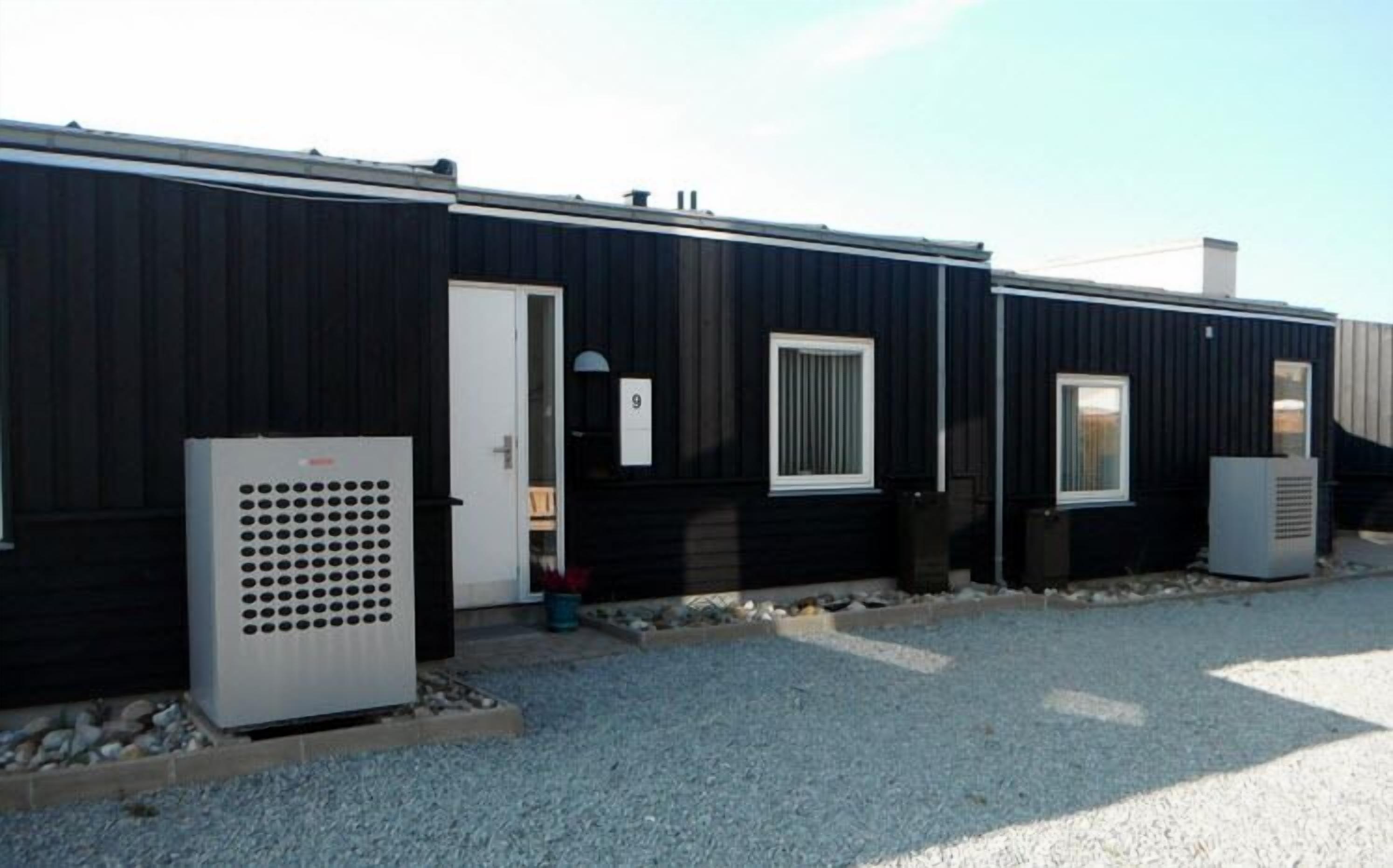 A row of modular buildings with a dark exterior, a white door, and a window with vertical blinds.