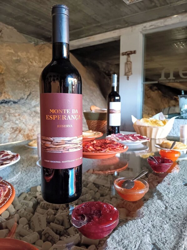 A bottle of Monte da Esperança Reserva wine with a rustic stone background and various food items. - Monte da Esperança (Arronches)