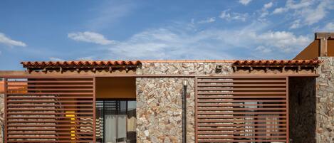 A modern building with a stone facade, wooden slats, and a tiled roof.