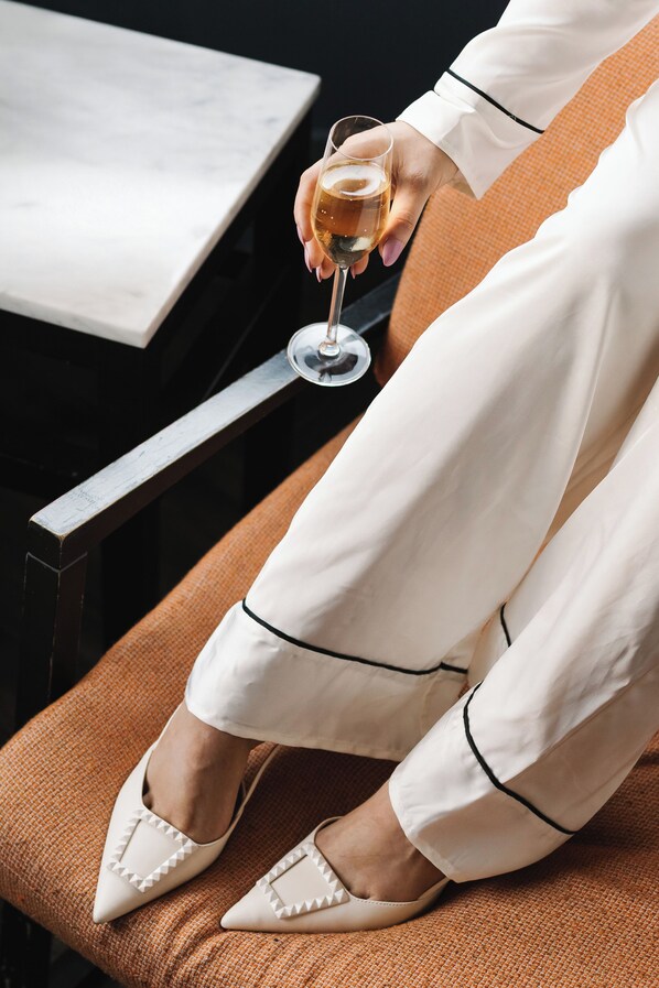 A person seated on a brown cushioned chair, holding a glass of white wine. - The Dean Dublin Centre (Dublin)