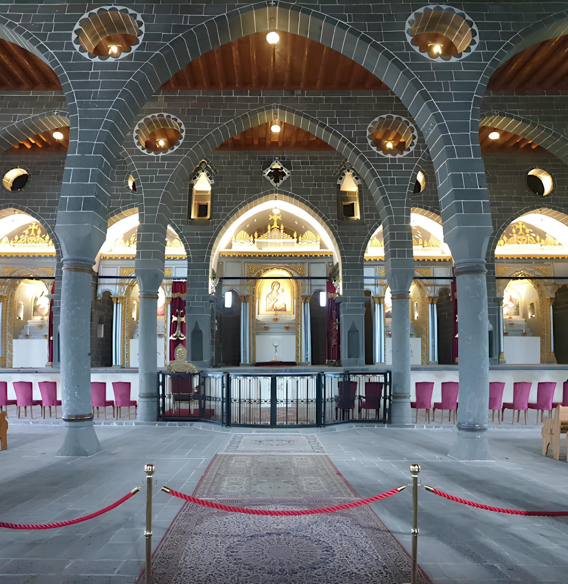 A church interior with arched ceilings, a central altar, and rows of pews.