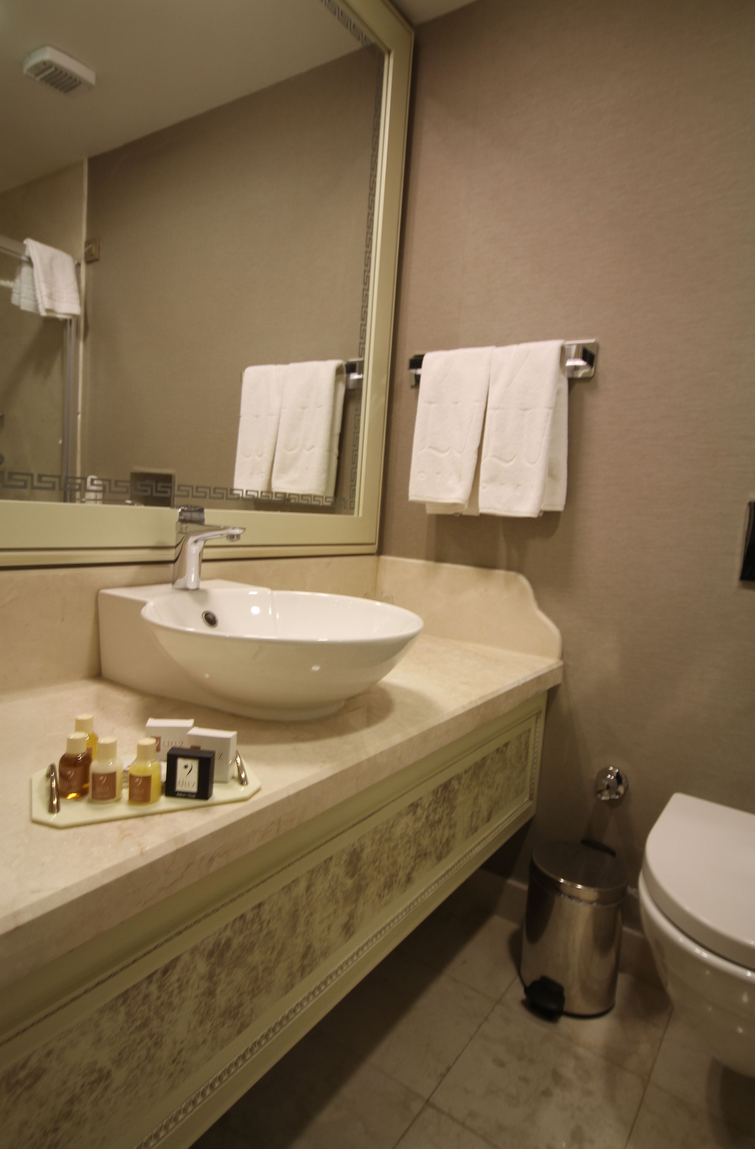 Un baño con lavamanos, espejo y perchero para toallas.
