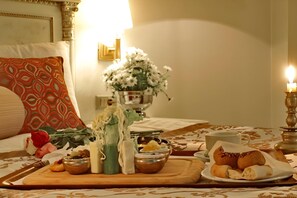 A dining table set with a variety of food items, including a plate of pastries, a bowl of nuts, and a vase of flowers. - Demir Hotel (Diyarbakir)