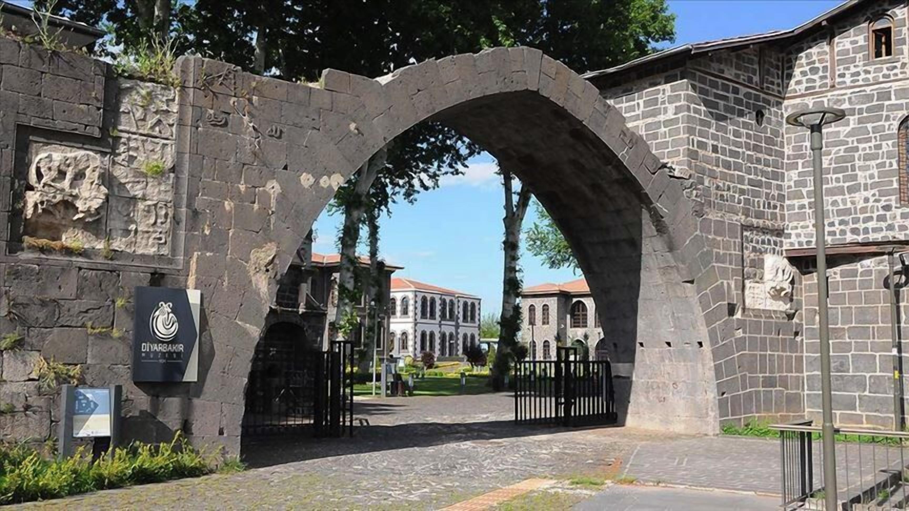 An arched stone gateway leading to a building with classical architecture.