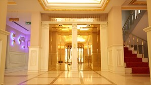 A grand lobby with a marble floor, a staircase with red carpeting, and a sign for 'Lobster & Cafe'. - Demir Hotel (Diyarbakir)