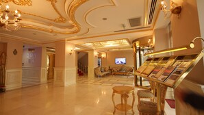 A spacious lobby with a grand chandelier, a reception desk, and a seating area with sofas. - Demir Hotel (Diyarbakir)