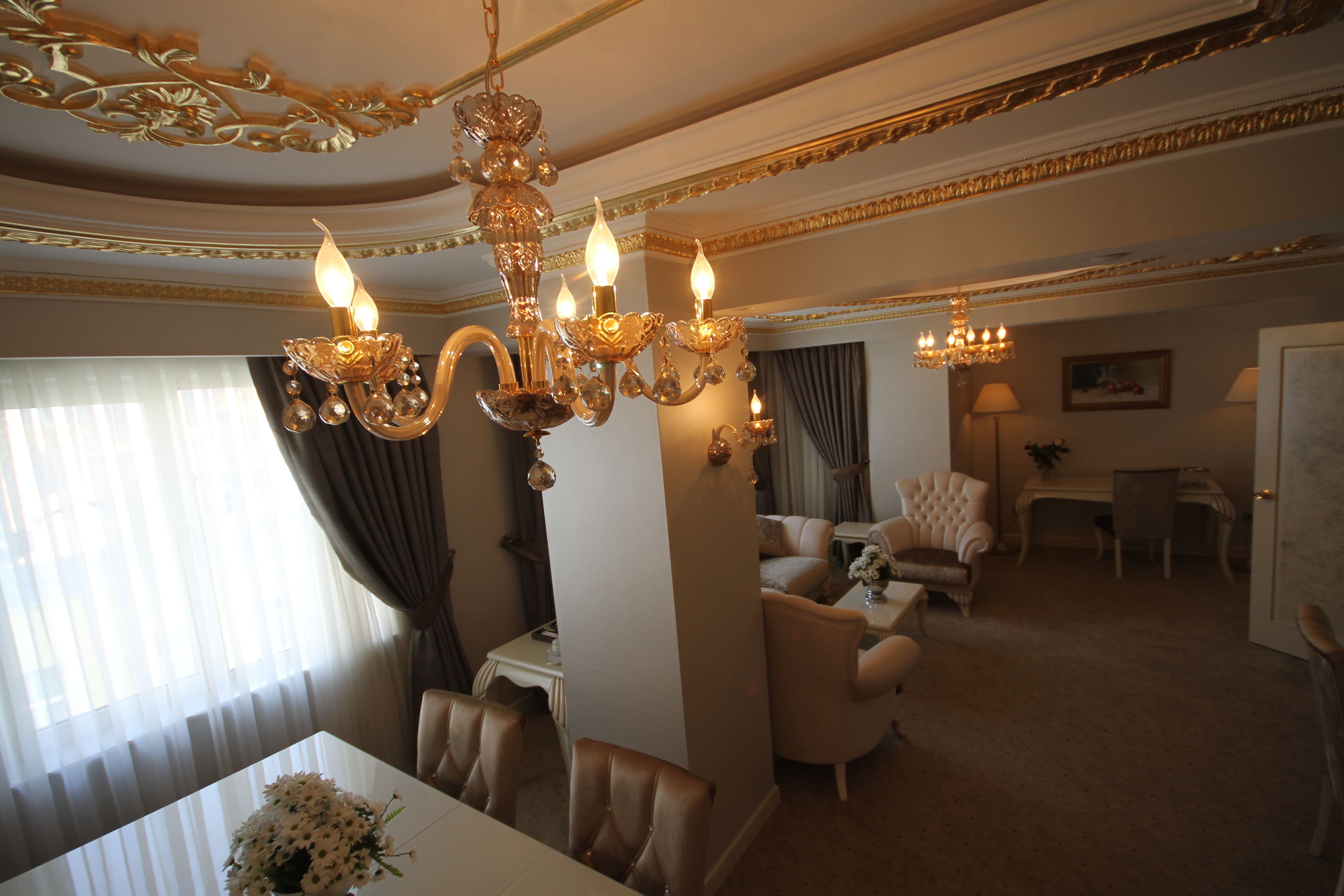 A luxurious living room with a chandelier, a dining area, and a seating arrangement.