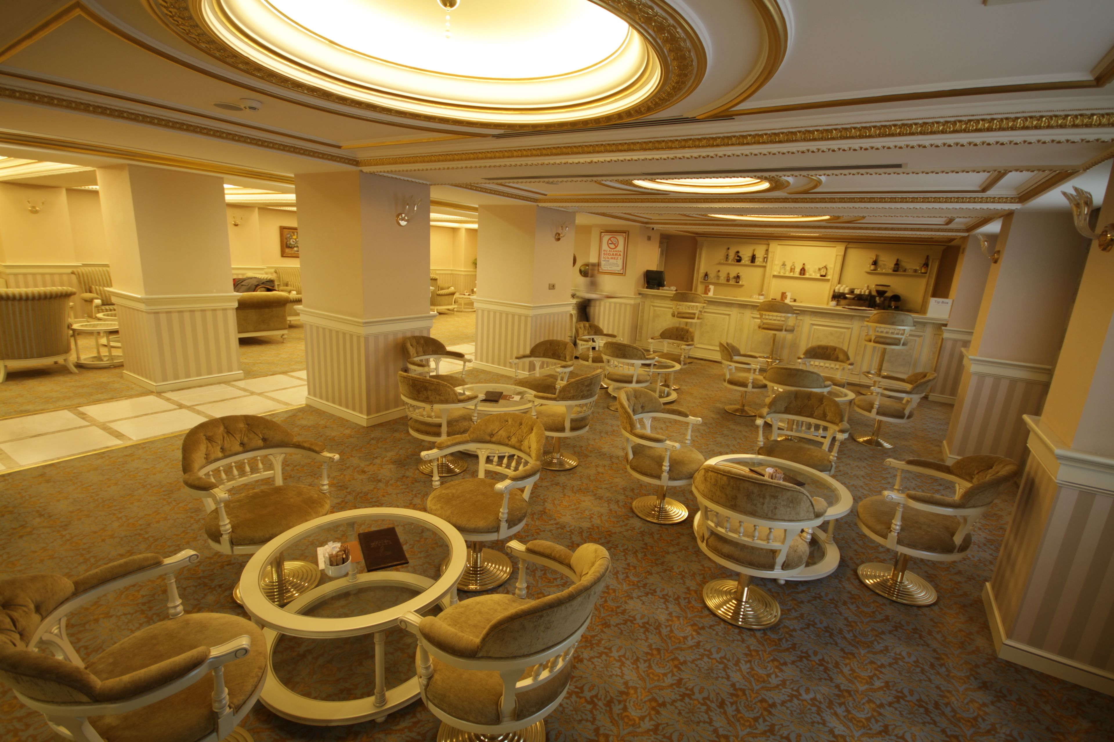 Un vestíbulo de hotel con varias zonas de estar, una recepción y un bar.